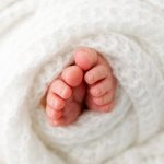 newborn baby toes wrapped in a knitted white blanket